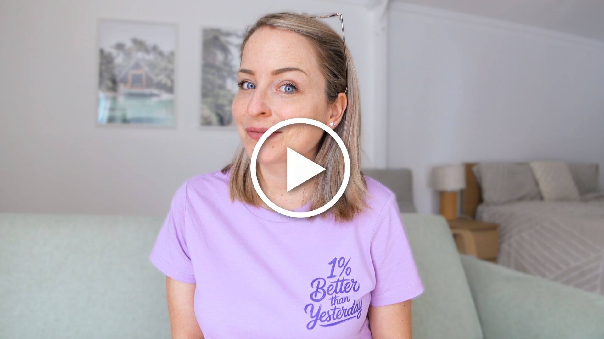 YouTube Image Maggie Stara in purple shirt that says 1% better than yesterday sitting on a sage couch.